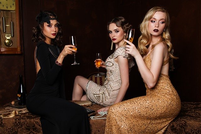 Tri ženy v sexy šatách, s výrazným mejkapom držia v rukách poháre s vínom.jpg