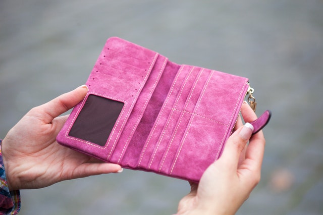 Žena drží v rukách koženú ružovú peňaženku